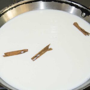 milk in skillet with cinnamon sticks