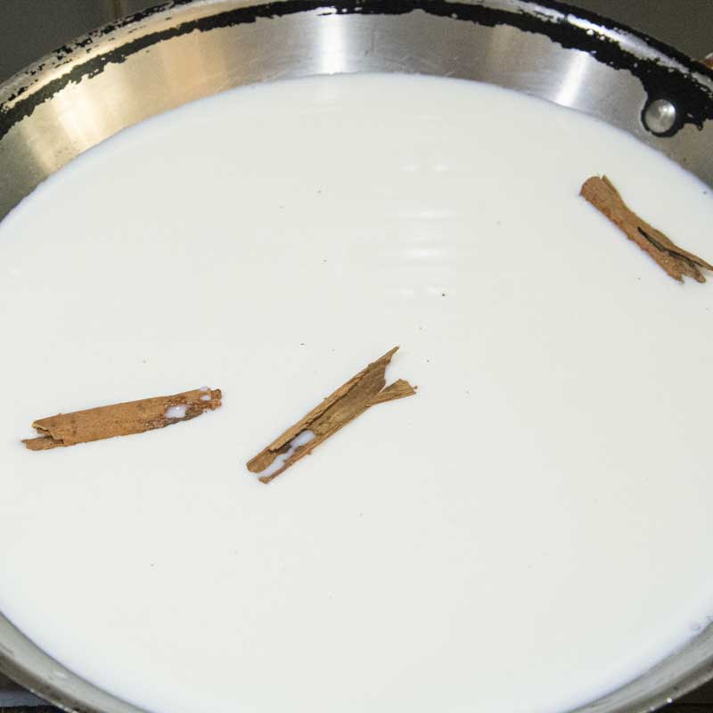 milk in skillet with cinnamon sticks