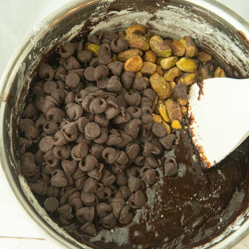 folding chocolate chips and pistachios into brownie batter