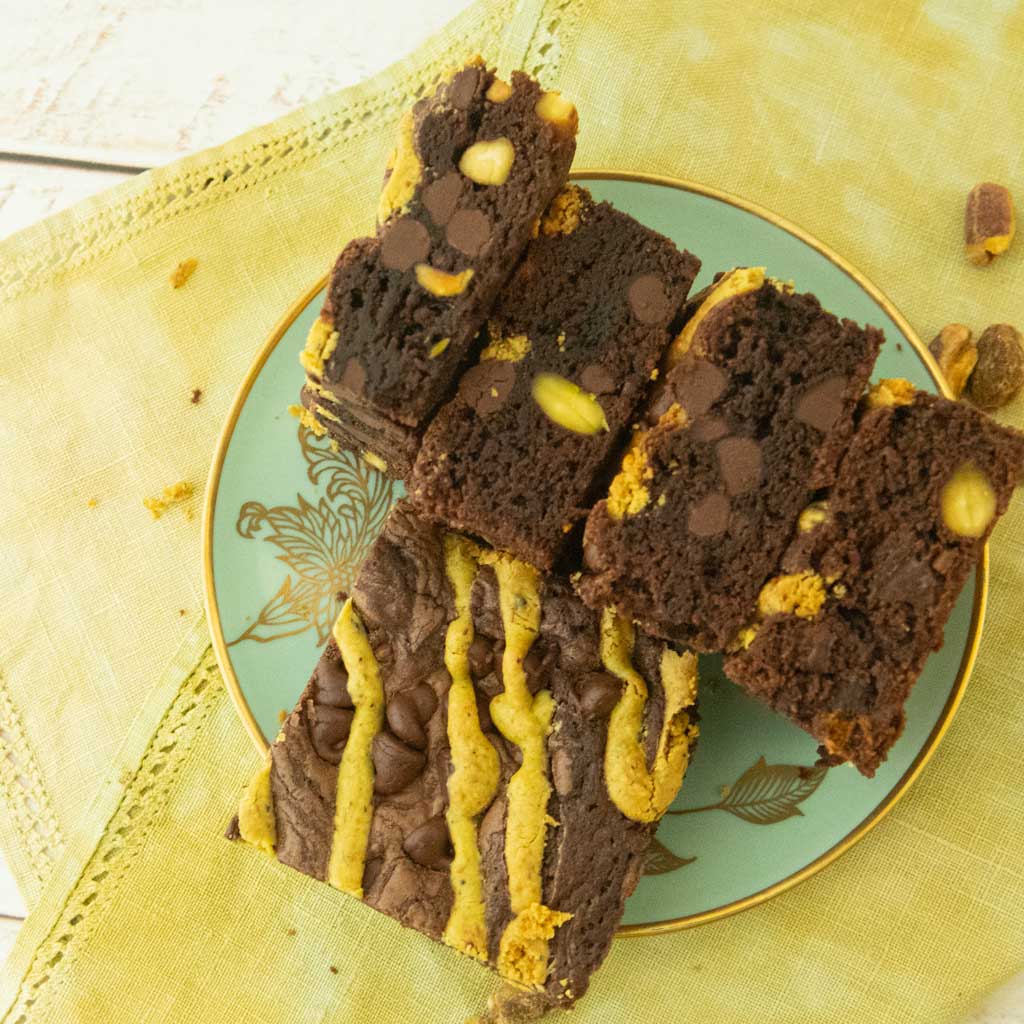 pistachio brownies cross section stacked horizontally on plate with one top view pistachio brownie