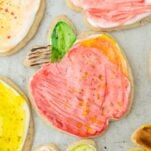 apple shaped red cookie decorated with watercolor painted royal icing