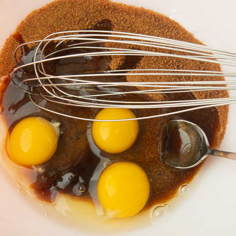 whisking eggs, vanilla, and brown sugar into butter and chocolate