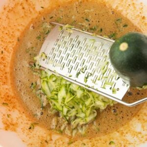 grating zucchini into batter for zucchini bread