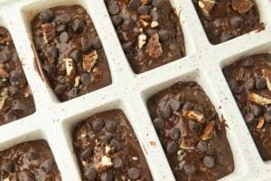 chocolate zucchini bread in pan before baking topped with pecans and chocolate chips
