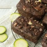 slices of zucchini next to small loaves of chocolate zucchini bread topped with chocolate chips and chopped pecans