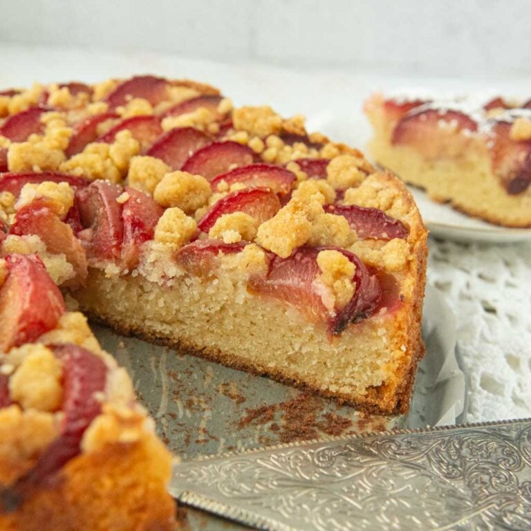 closeup of plum cake with streusel with slice cut from the cake, slice of plum cake out of frame, pie server