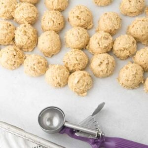 oatmeal cookie dough scoops on sheet tray next to cookie scoop