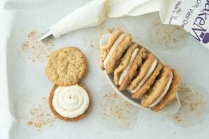 pastry bag, oatmeal cookie topped with ermine frosting with another oatmeal cookie slightly offset to show how to fill oatmeal cream pies, a dish of oatmeal cream pies