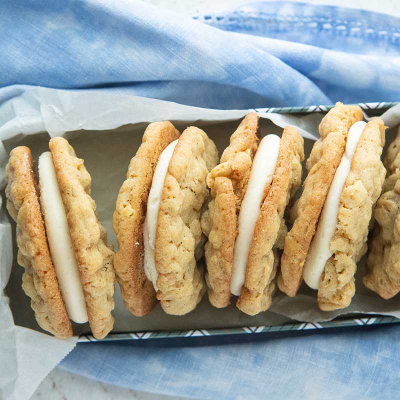 oatmeal cream pies in tin lined with parchment on blue napkin