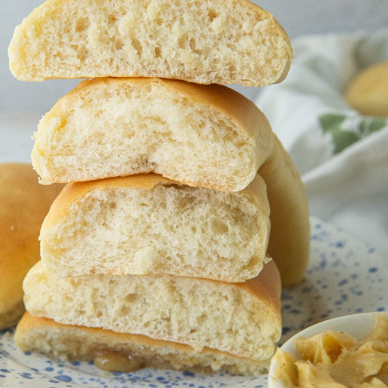 stack of texas roadhouse rolls, cut in half to show texture next to honey cinnamon butter