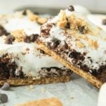 closeup of s'mores brownies stacked, shown from the side to show layers of marshmallow, graham cracker, and brownie