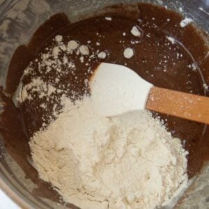 adding flour and white chocolate chips to brownie batter