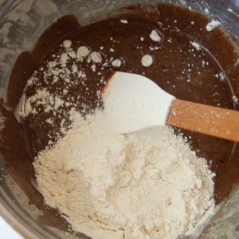 adding flour and white chocolate chips to brownie batter