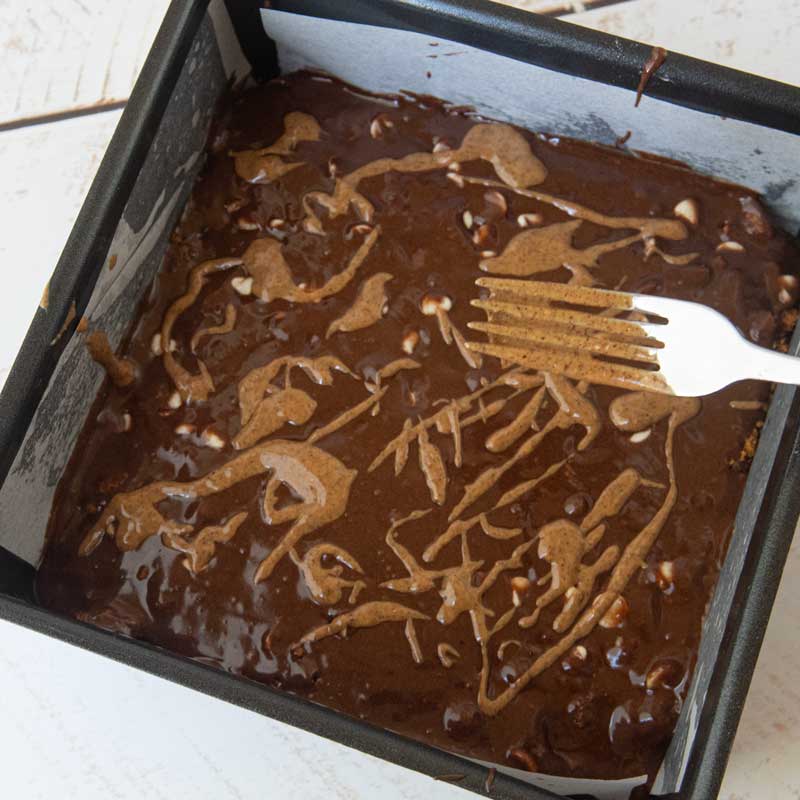 drizzling almond butter over brownie batter
