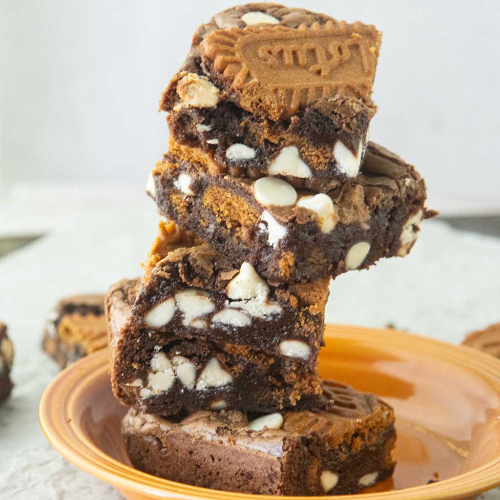 stack of biscoff brownies on orange plate, showing sides