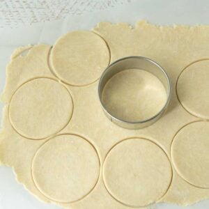 biscuit cutter on top of cream cheese pastry dough, cutting out circles of dough