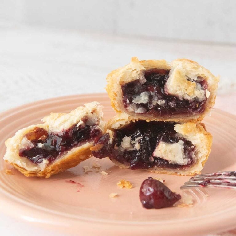stack of mini cherry pies cut in half on plate, fork