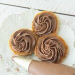 swirls of chocolate ermine frosting on backs of pumpkin oatmeal cookies, piping bag filled with chocolate ermine frosting