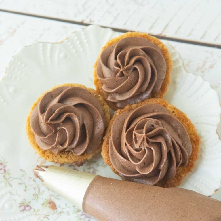 swirls of chocolate ermine frosting on backs of pumpkin oatmeal cookies, piping bag filled with chocolate ermine frosting