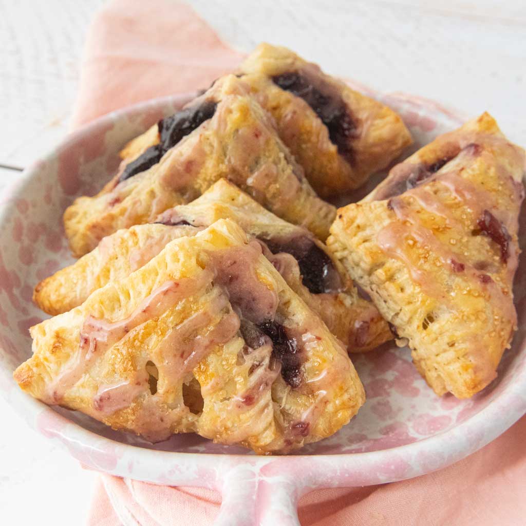homemade baked cherry turnovers in pink and white speckled plate