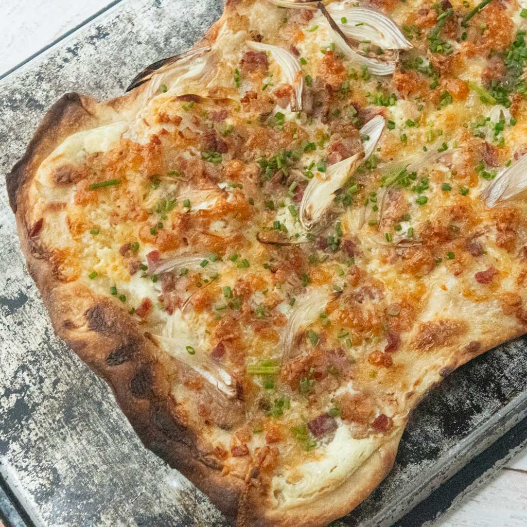 whole flammkuchen with butterkase on sheet tray