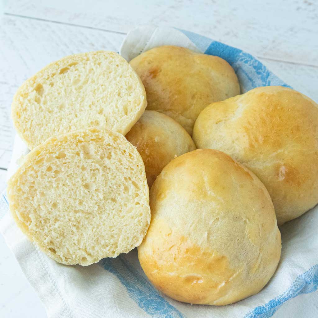 potato buns in basket, one cut to reveal inner fluffy texture
