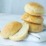stack of potato buns next to one potato bun, cut to show texture