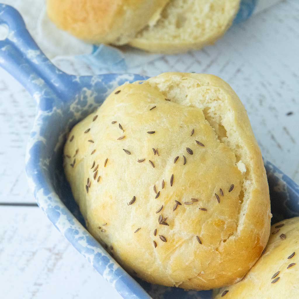 potato buns topped with caraway seeds in blue dish