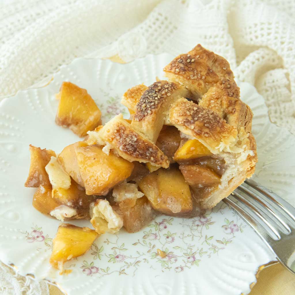 slice of peach pie with a lattice top on plate, fork