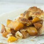 closeup of slice of peach pie with a lattice top on plate