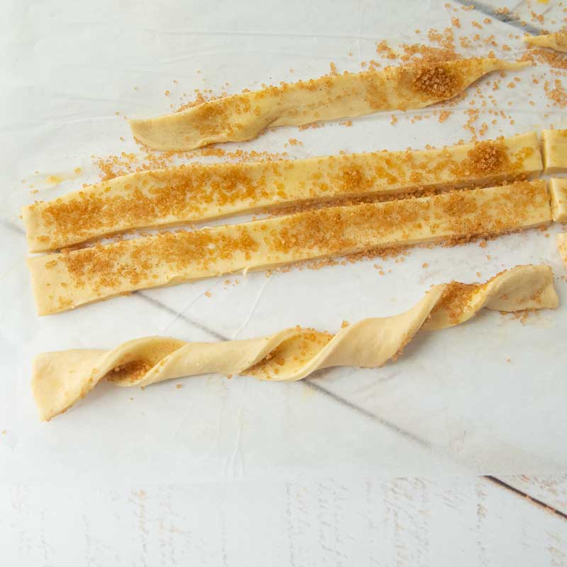 twisting puff pastry strips covered in cinnamon sugar