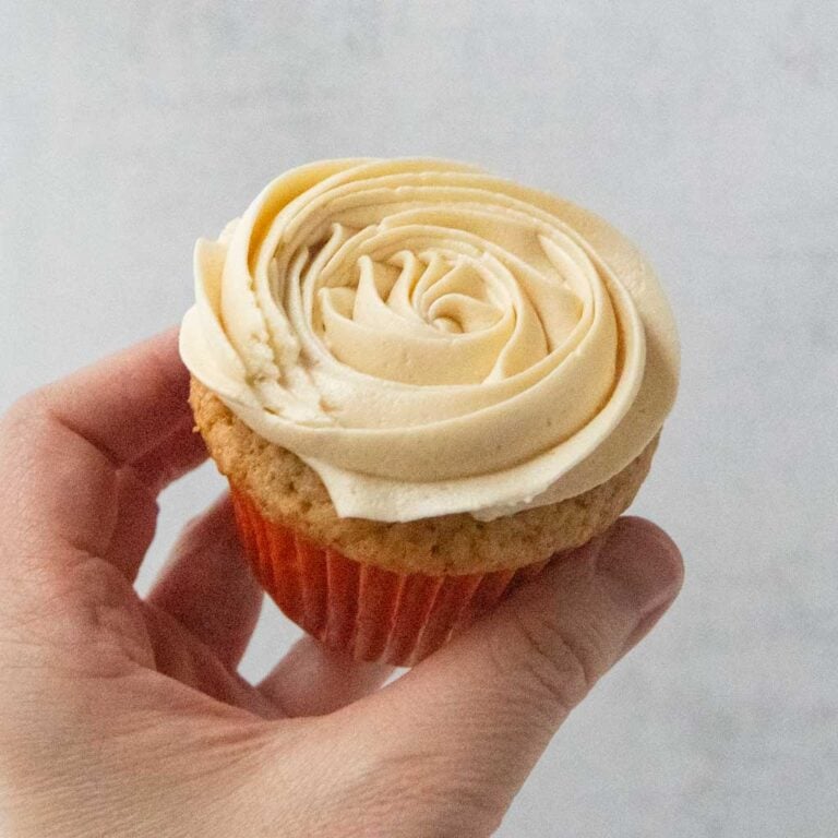 hand holding apple butter cupcake topped with maple buttercream