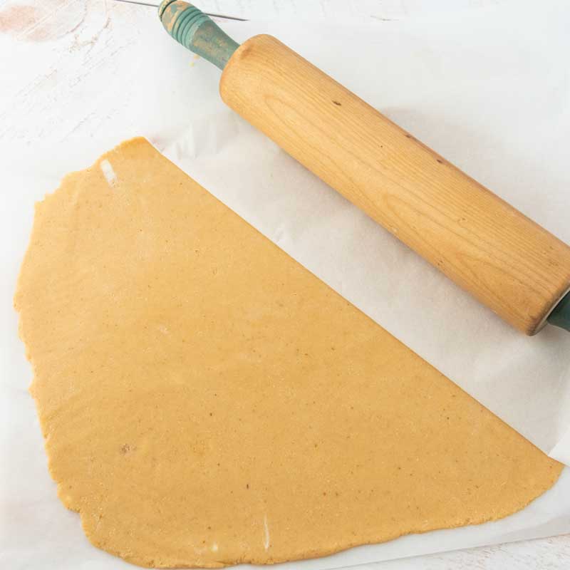 pumpkin cutout cookie dough rolled between pieces of parchment