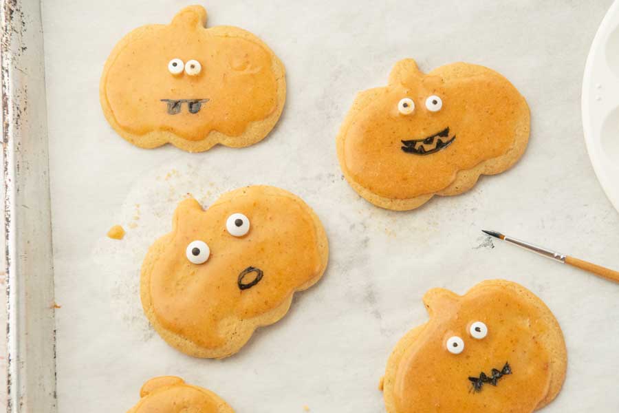 painting faces on pumpkin cutout cookies
